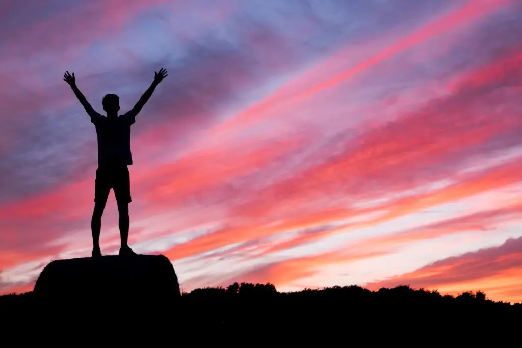 Man standing in front of a sunset, conquering his internal issues and continuing to work