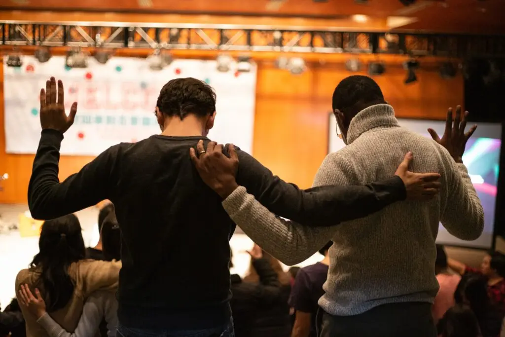 Two young men lifting their hands in prayer representing Dare 2 Share's blog on 4 way to pray for a successful, evangelistic youth group