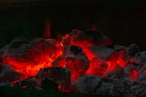 Glowing red hot coals in a dark fire pit, illustrating the biblical metaphor of doing good deeds from Proverbs 25