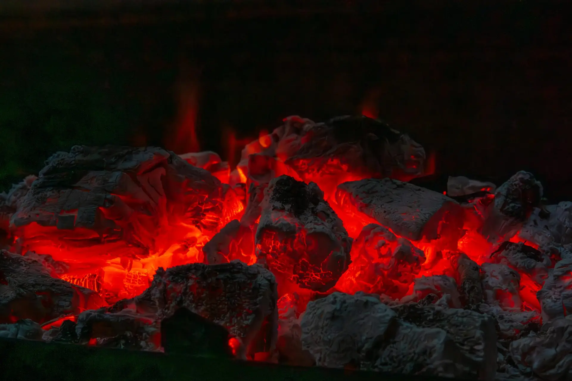 Glowing red hot coals in a dark fire pit, illustrating the biblical metaphor of doing good deeds from Proverbs 25